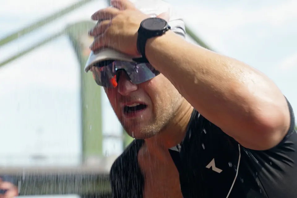Triathlet kühlt sich beim Laufen mit Wasser ab, Szene aus „Road to Ironman“