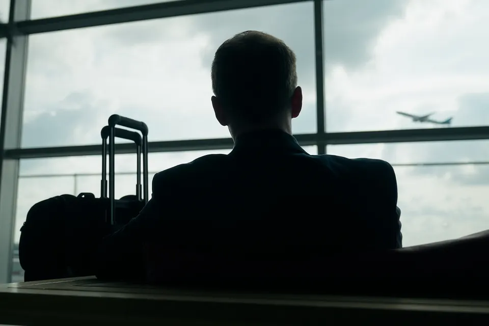 Silhouette eines Reisenden am Flughafenfenster mit startendem Flugzeug, Wissenschaftsdoku für die TUI Group