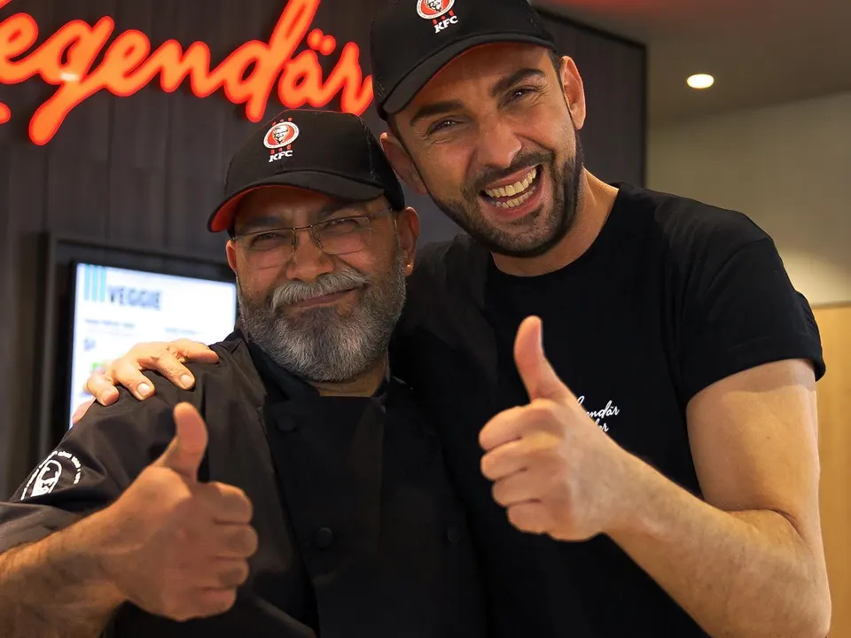 Zwei KFC-Mitarbeiter lachen und zeigen Daumen hoch