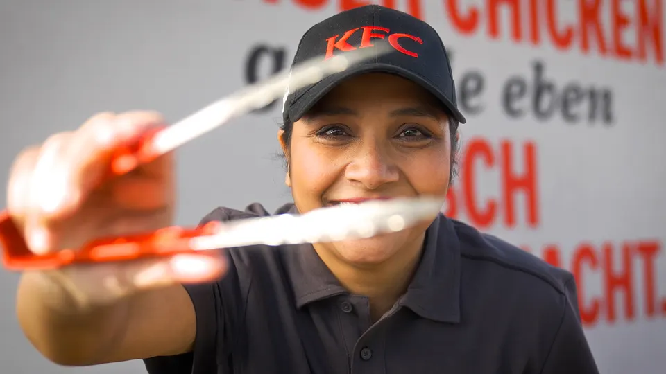 KFC-Mitarbeiterin hält eine Grillzange in die Kamera, Recruitingfilm für KFC Deutschland