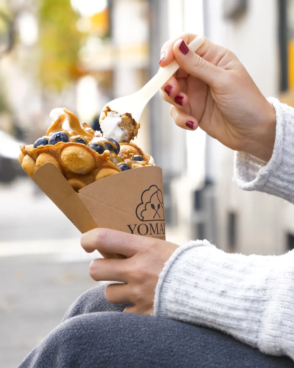 Hand hält eine Bubble Waffle mit Eis, Foodshot für Social Media