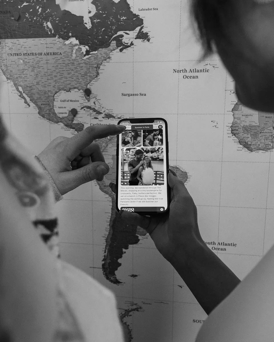 Hand hält ein Smartphone über eine Weltkarte, Schwarzweiß